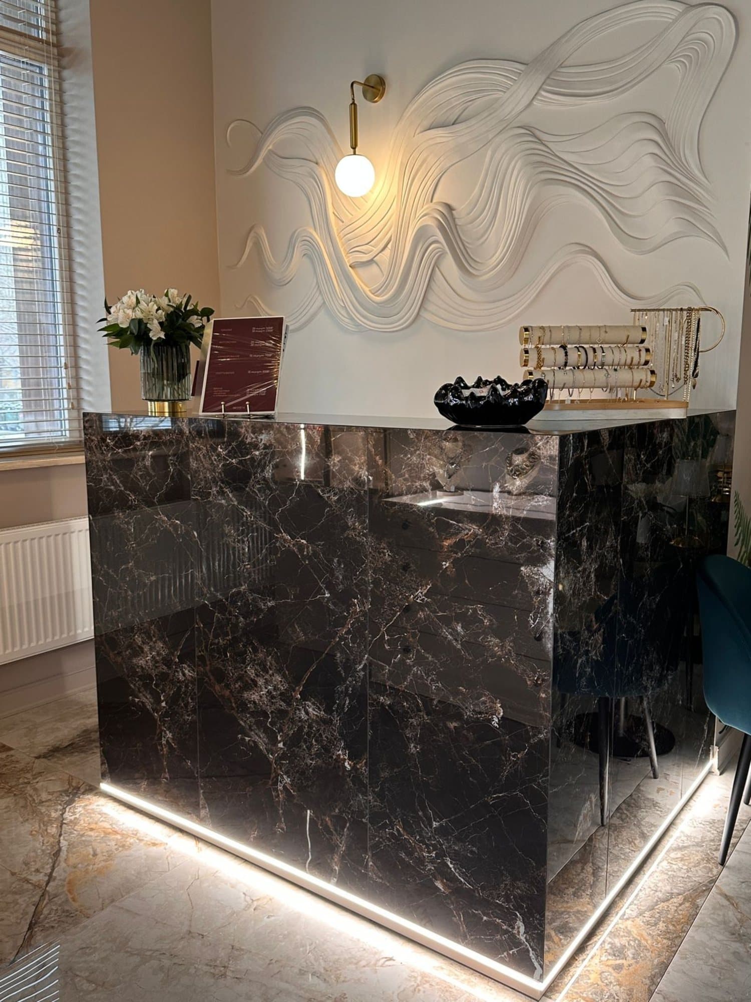 Ресепшн BEUTEM: стойка из тёмного мрамора и рельефная стена в виде волн